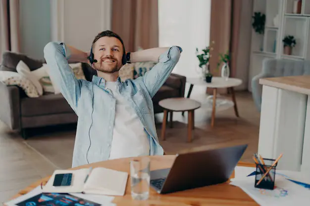 A focused freelancer working on a laptop at a cozy workspace with coffee, notebook, and digital tools around.