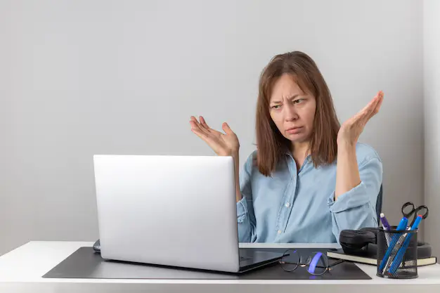 Freelancer looking frustrated while using Fiverr platform, with declining sales graph on screen – representing common Fiverr mistakes that hurt earnings